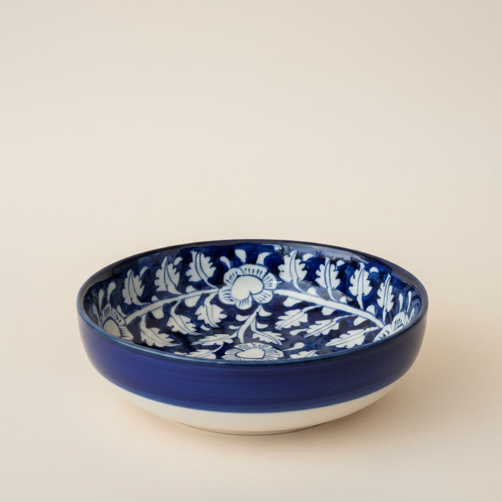 A round ceramic bowl with a deep cobalt blue glaze and a white floral pattern