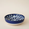 A round ceramic bowl with a deep cobalt blue glaze and a white floral pattern