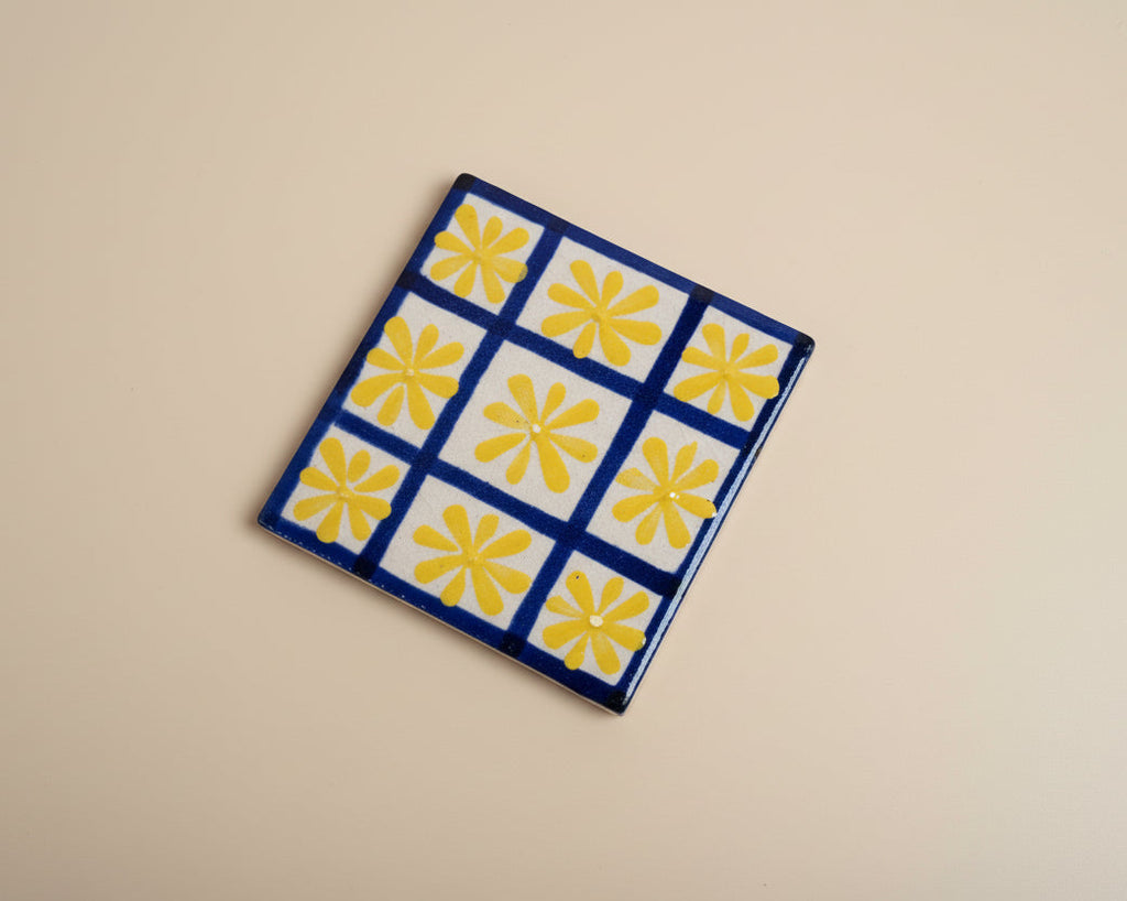 Handmade Pottery Tile with a blue square pattern and yellow suns inside