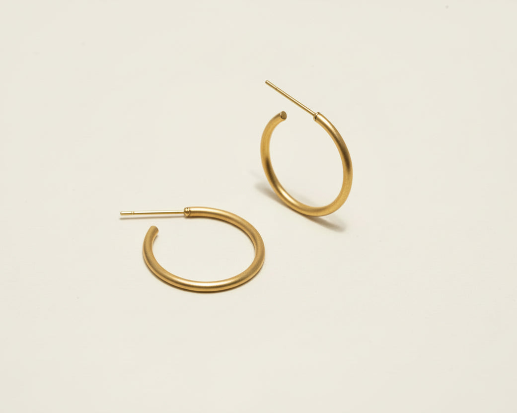 Gold hoop earrings on a beige background