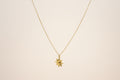 Gold necklace with a sun pendant on a light beige background