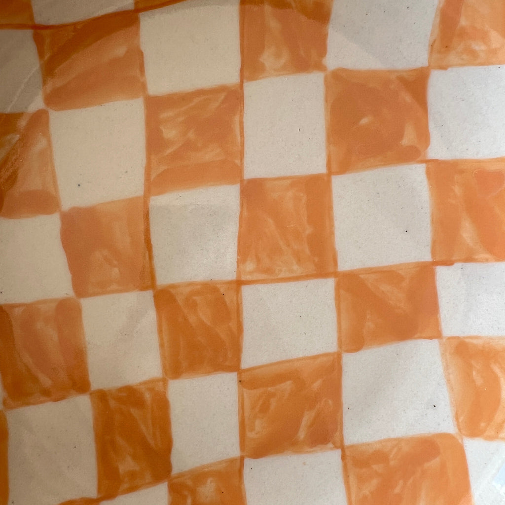 A close-up of a checkered pattern with alternating orange and off-white squares, showing a slightly textured surface.