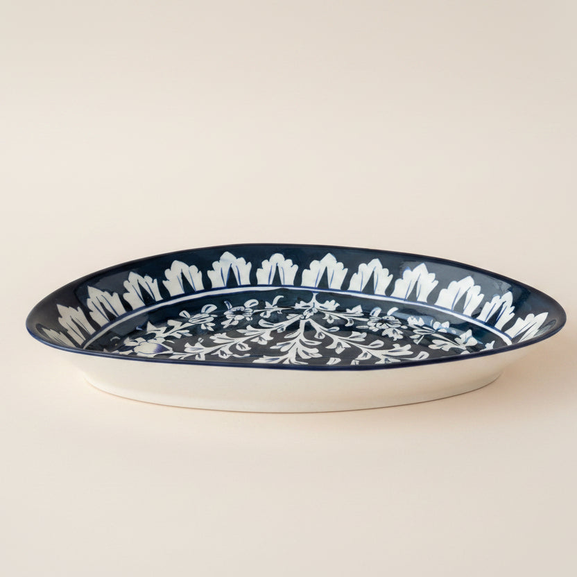 An oval ceramic serving platter with a dark navy blue and white floral pattern.
