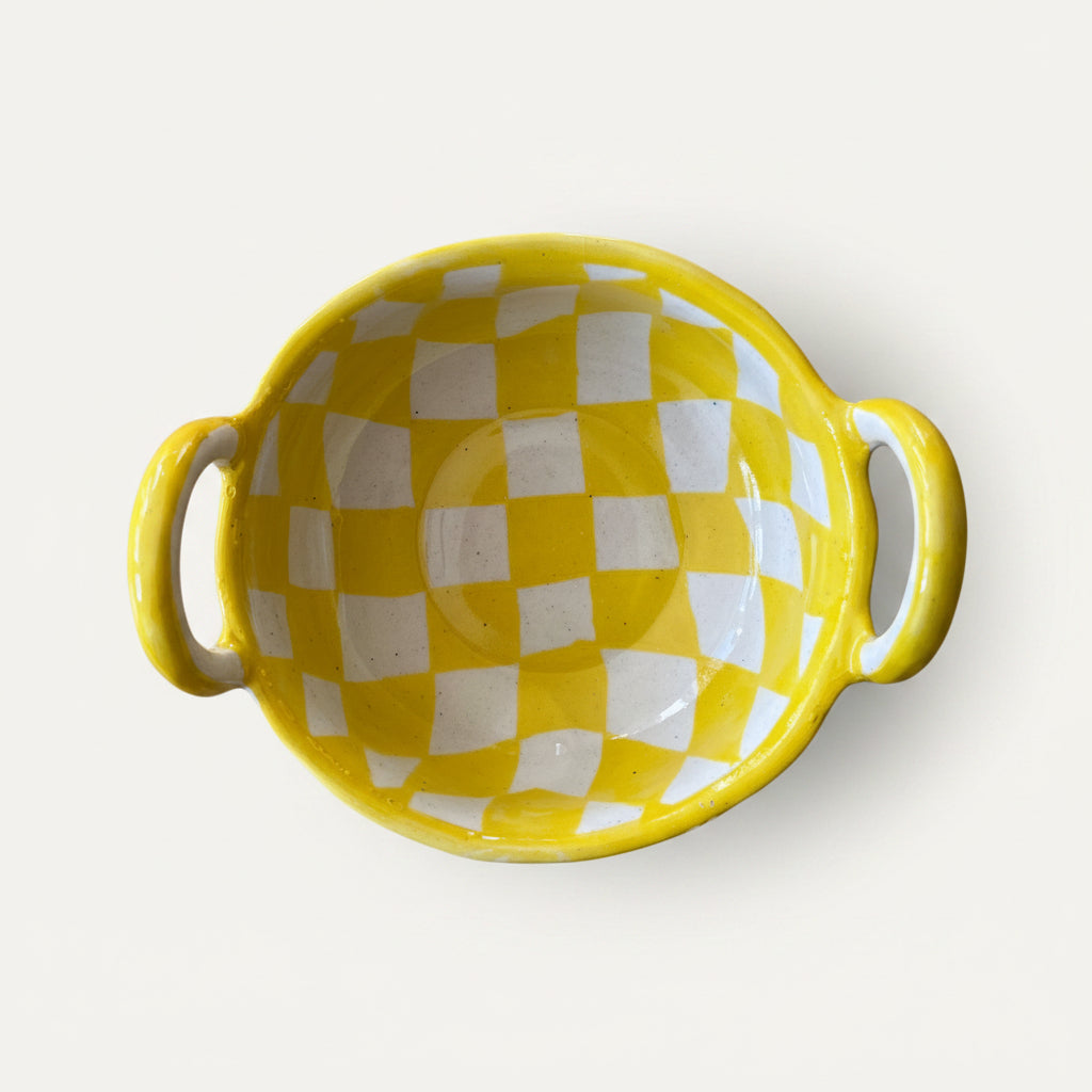 A yellow and white checkered ceramic bowl with two side handles.