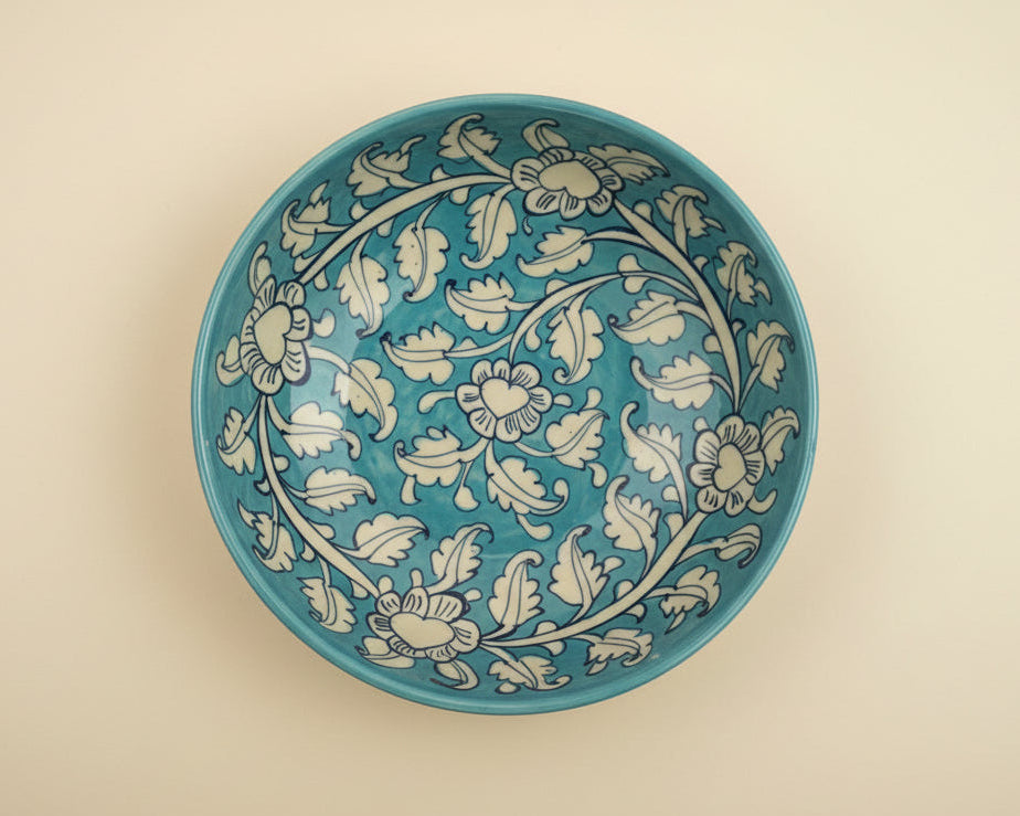 Decorative handmade pottery bowl with floral patterns on a plain background