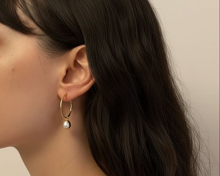 Woman wearing a gold earring with a plain background