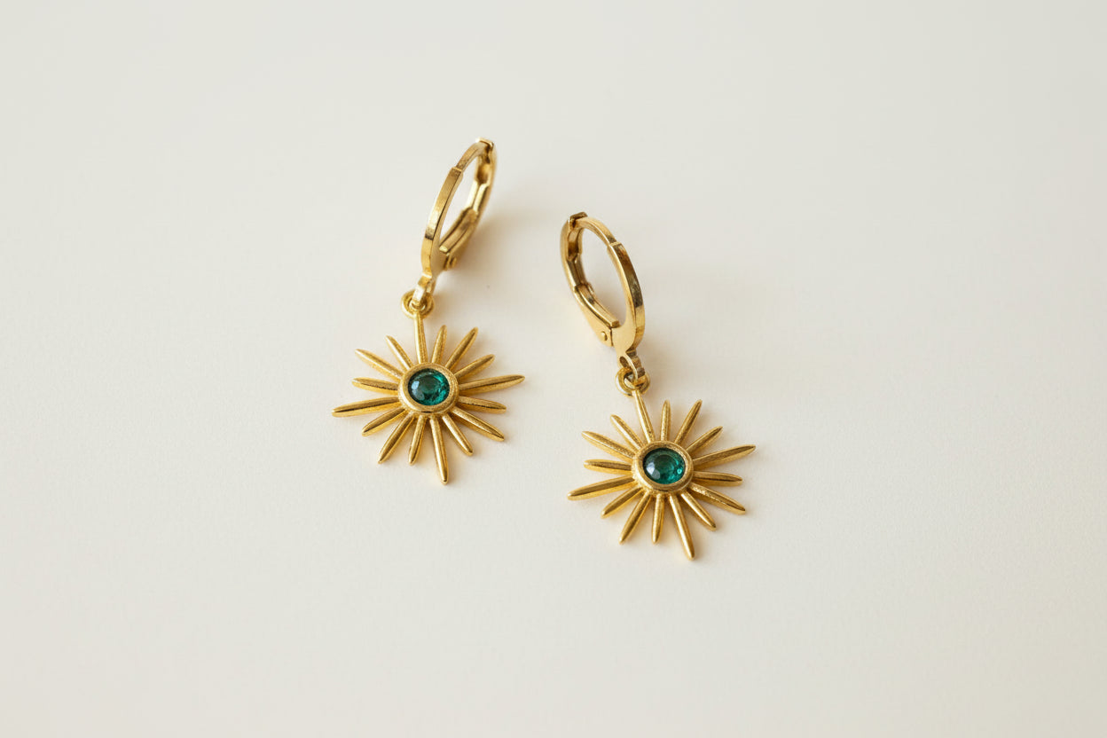 Golden Earrings with a small hoop and a golden sun shaped pendant with a green stone in the middle